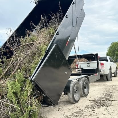 Mako dump truck raised and unloading branches and brush onto a landscaping pile during a Killeen-area job